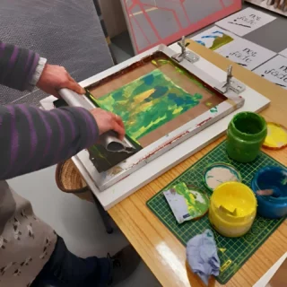 This week’s #craftfocus is screen printing. 

Screen printing is a printing technique that uses a mesh screen, ink, and a squeegee to transfer a stencilled design onto a flat surface.

The basic method involves creating a stencil on a fine mesh screen, then pushing ink (or paint, in the case of artwork and posters) through to create an imprint of the design on the surface beneath. 

The way the stencil is created can vary depending on the materials used. Different stencilling techniques include using masking tape or vinyl to cover the desired areas of the screen, painting the stencil onto the mesh using ‘screen blockers’, such as glue or lacquer, and using a light-sensitive emulsion to create a stencil – then developed in a similar way to a photograph.

Some designs may use only one shade of ink, or many – in which case each colour must be applied in individual layers using separate stencils for each ink. One reason screen printing is so widely used is due to its ability to produce vivid colours, even on darker fabrics.

Issues affecting the viability of screen printing include competition with digital printing technologies, which offer quick turnarounds and the ability to print complex designs with low setup costs. This has also resulted in a reduced number of skilled practitioners.

Traditional screen printing uses inks and chemicals that can be harmful to the environment, which is why it is crucial for screen printing businesses to invest in environmentally friendly alternatives.

Images: Sarah Martinez @berkshire_printmakers

#heritagecrafts #craftfocus #screenprinting